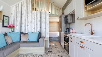 A compact kitchen with white cabinets, a copper faucet, and a patterned floor.