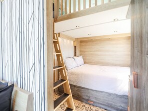 A loft-style bedroom with a wooden ladder, a bed, and a sloped ceiling. - Posh Pod (Cemaes Bay)