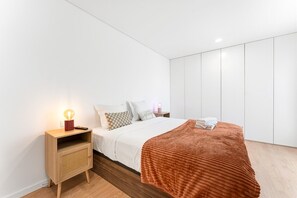 Un dormitorio moderno con cama, mesita de noche, lámpara y armario.