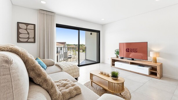 A modern living room with a sofa, a TV, and a balcony with a view. - GuestReady-Sunny Modern Retreat in Mira (Mira)
