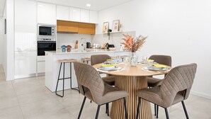 A modern kitchen with white cabinets, a wooden dining table, and four chairs. - GuestReady-Sunny Modern Retreat in Mira (Mira)