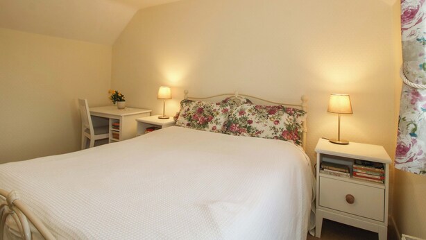 A bedroom with a bed, two bedside tables with lamps, a chair, and a desk. - Ivy Cottage (Church Stretton)