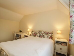 Une chambre à coucher comprenant un lit, deux tables de chevet avec des lampes, une chaise et un bureau.