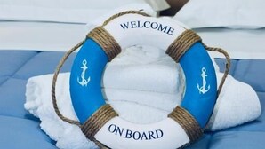 A bed with a life preserver-shaped pillow with 'WELCOME ON BOARD' text and anchor symbols. - B&B le Pontine (Gaeta)