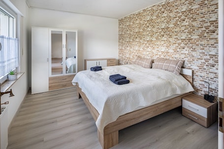 A bedroom with a brick wall, wooden bed frame, and a bedside table with a lamp.. Apartment 'Fewo Zum Eisenstollen' with Shared Terrace and Wi-Fi
