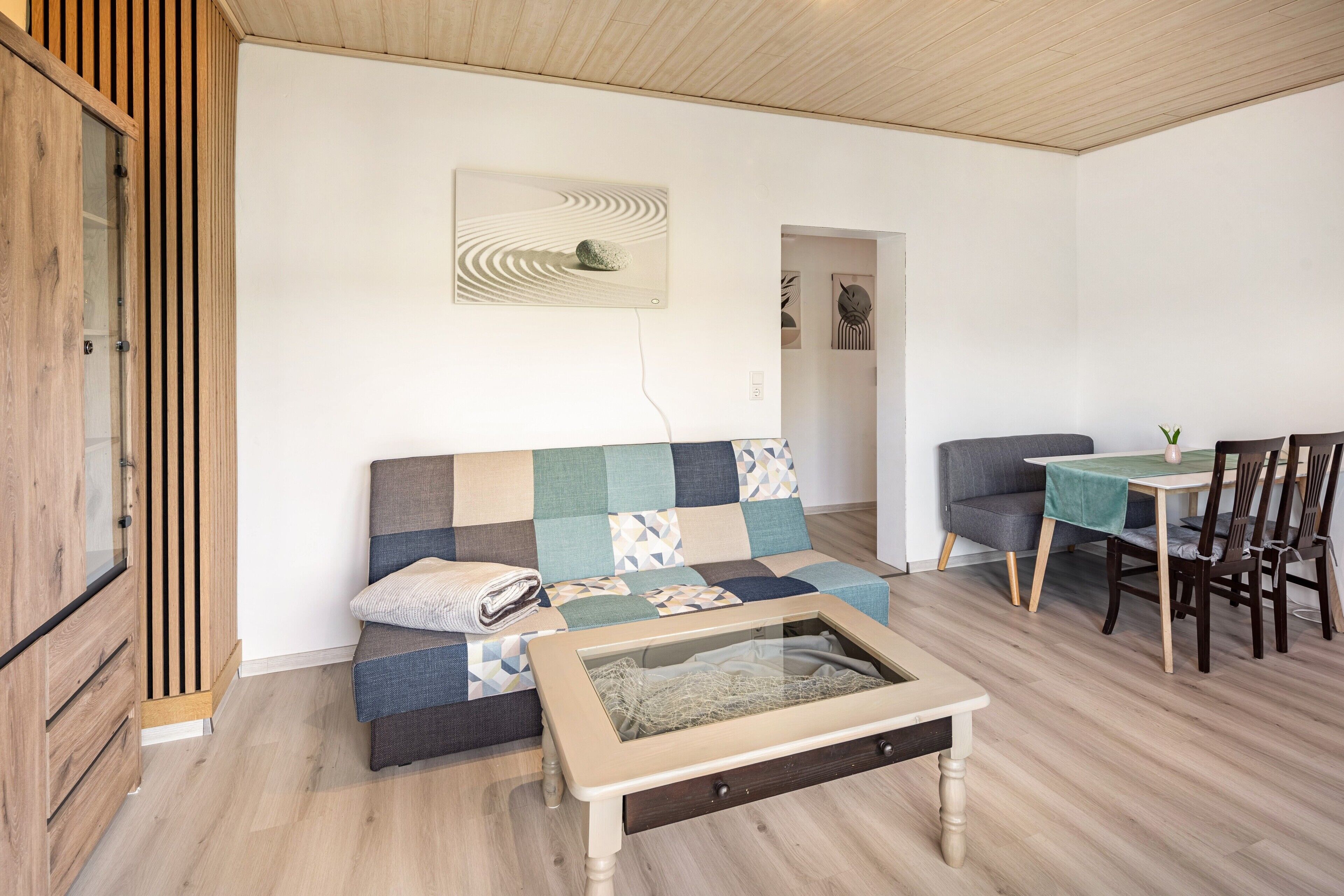 Ein gemütlicher Wohnbereich mit Sofa, Couchtisch, Esstisch mit Stühlen und Schrank.