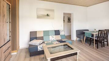 Ein gemütlicher Wohnbereich mit Sofa, Couchtisch, Esstisch mit Stühlen und Schrank.