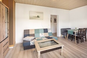 Un salon confortable avec un canapé, une table basse, une table à manger avec des chaises et un meuble.