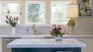 A kitchen with a large island, two bar stools, a double sink, and pendant lighting. - Inn at Park Winters (Winters)
