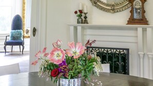 A dining area with a chandelier, a mirror, and a vase of flowers on a table. - Inn at Park Winters (Winters)
