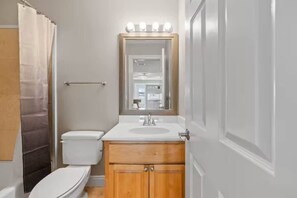 Un bagno con il water, un lavandino, uno specchio e una tenda doccia.
