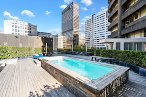 A rooftop pool with a wooden deck, surrounded by city buildings. - One Thibault 1927 (Cape Town)