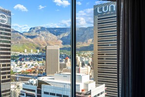 A cityscape with mountains in the background, viewed through a window with a building labeled 'tun' on the right. - One Thibault 1927 (Cape Town)