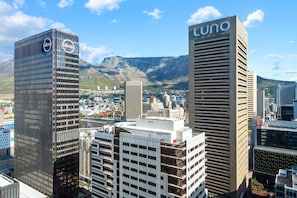 Eine Stadtansicht mit markanten Gebäuden, darunter ein hohes Bauwerk mit 'cuno'-Beschilderung und ein weiteres mit 'absa'-Branding.