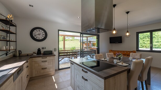 Una cocina moderna con una isla central, armarios de madera, horno empotrado y un ventanal con vistas a un patio.