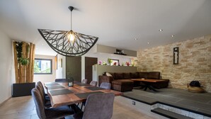 Una sala de estar moderna con comedor, pared de piedra y una lámpara colgante.
