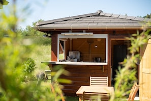 Una cabaña de madera con balcón, una mesa y una silla.