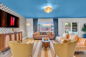 Uma sala de estar com televisão, sofás, mesa de centro e parede estampada.