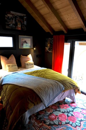 Een kamer met een bed, kussens, een raam en een deur.