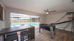 A room with a pool, a foosball table, and a table with chairs. - Sarasota House With Pool (Southgate)