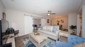 A living room with a sofa, coffee table, TV, and a ceiling fan. - Sarasota House With Pool (Southgate)