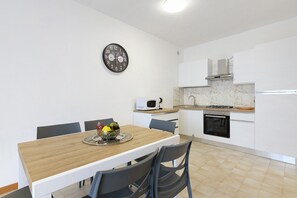 Une cuisine moderne avec des meubles blancs, un four à micro-ondes, une cuisinière et une horloge murale.