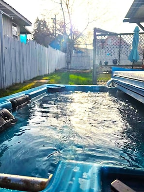 Ein Schwimmbad mit Holzterrasse und einem Zaun im Hintergrund.