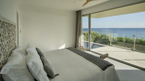 Ein Schlafzimmer mit einem großen Bett, einem Deckenventilator und einem Balkon mit Meerblick.