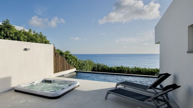 Eine Dachterrasse mit Whirlpool, Liegestühlen und Meerblick.