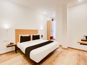 Ein Hotelzimmer mit Bett, Nachttischen, einer Ablage, einem Holz-Kopfteil, einer Wandleuchte und einem Holzschrank.