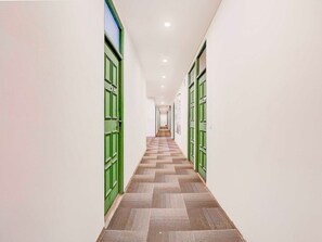Ein Flur mit grünen Türen, einem gemusterten Boden und einer Decke mit eingelassenen Leuchten.