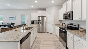 A modern kitchen with white cabinets, stainless steel appliances, and a granite countertop.