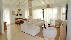 Un salón amplio con un sofá grande, una mesa de comedor y un televisor montado en la pared.