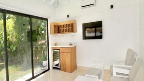 Una sala moderna con un gran ventanal, un mueble de madera, un televisor de pantalla plana y un sofá blanco.
