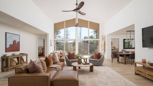 A spacious living room with a large sectional sofa, a round coffee table, and a ceiling fan. - Peaceful Pool and Tub Bliss with Majestic Thunder Mountain Views (Sedona)
