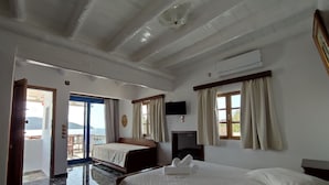 A hotel room with a bed, a TV, a ceiling fan, and a view of the sea. - Liva Mare Serifos (Serifos)