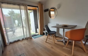 Ein Zimmer mit einer Schiebetür zum Außenbereich, einem Tisch mit einer Schüssel, zwei Stühlen und einem Spiegel an der Wand.