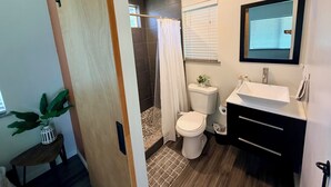 Ein modernes Badezimmer mit Dusche, Toilette, Waschbecken und einem kleinen Topfpflanzen.