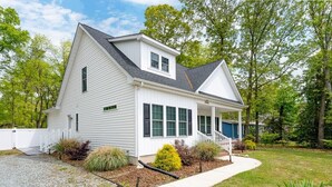 A single-story house with a front porch, a covered entryway, and a small front yard with landscaping. - Creature Comforts (Rehoboth Beach)