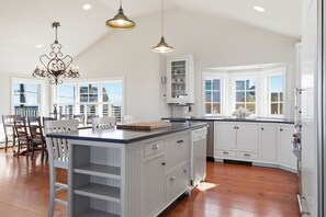 A spacious kitchen with white cabinetry, a central island, and pendant lighting. - Sun-Drenched Coastal Escape on Kennebunk Beach (Kennebunk)