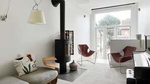 A modern living room with a black wood-burning stove, a sofa with patterned cushions, a wooden chair, and a dining table. - Downtown Toronto row house. Close to Ossington, Trinity Bellwood & BMO field. (Toronto)