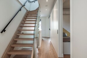 A modern staircase with glass railings, wooden steps, and a white interior.