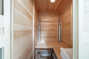 A sauna room with wooden walls and benches, equipped with ventilation systems.