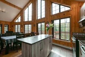 Un intérieur en bois comprenant une cuisine, un coin repas et de grandes fenêtres.