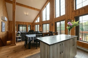 L’intérieur d’une cabane en bois comprend un coin repas, une cuisine et de grandes fenêtres.