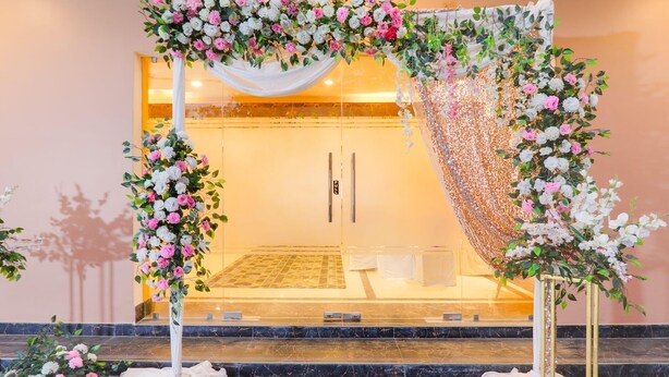 A wedding arch with floral arrangements and a mirrored backdrop. - Deluxe Veridian inn (Lucknow)