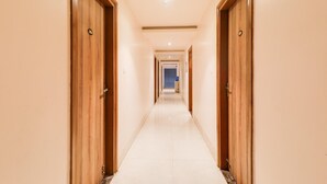 A hotel corridor with wooden doors, a tiled floor, and a ceiling light. - Deluxe Veridian inn (Lucknow)