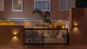 A hotel entrance with a decorative gate, a potted plant, and wall-mounted lights. - Deluxe Veridian inn (Lucknow)