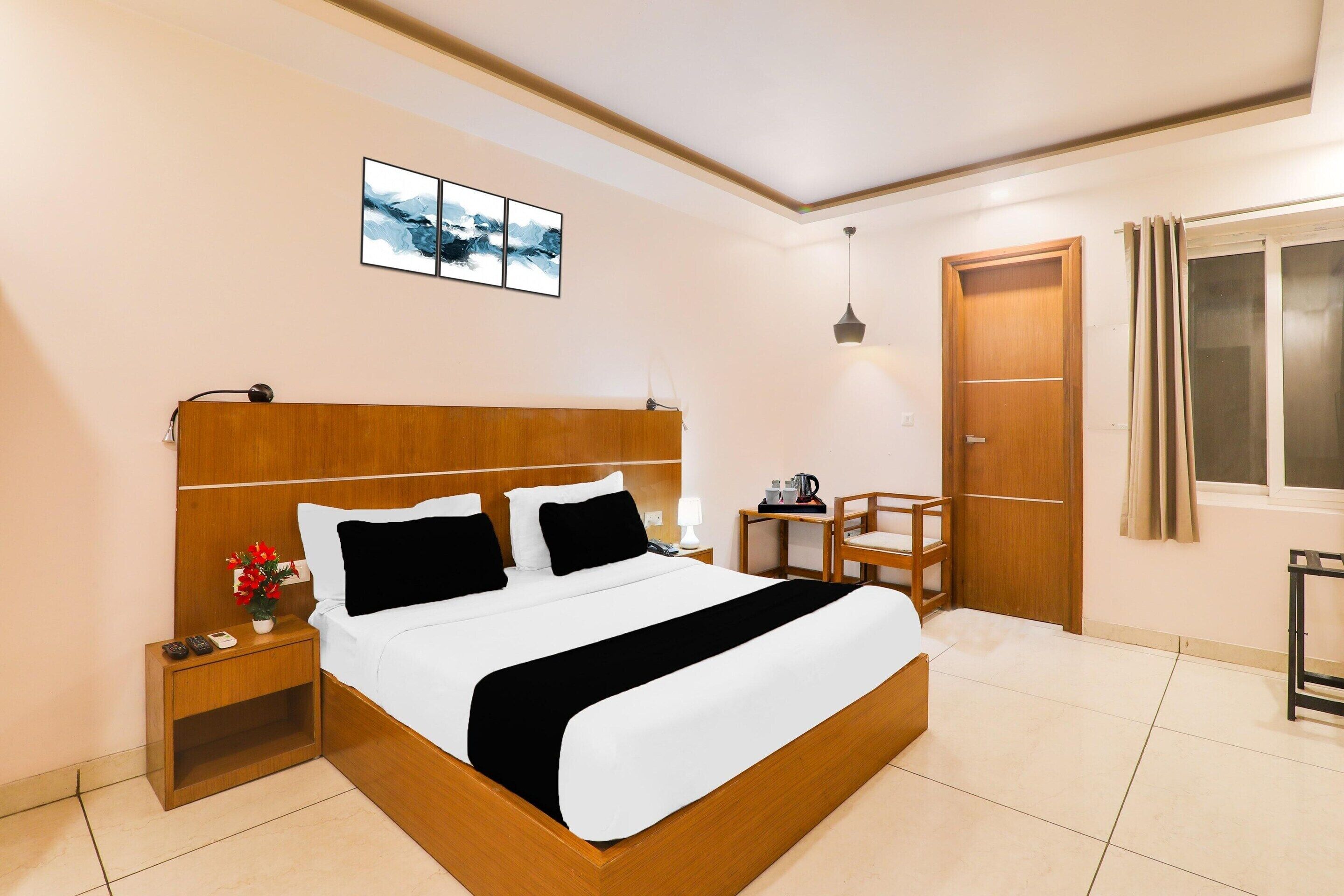 Una camera d'albergo ordinata con un letto in legno, comodino, lampada e un'opera d'arte appesa al muro.