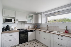 Une cuisine moderne avec des meubles blancs, un four à micro-ondes, une cuisinière et un évier.